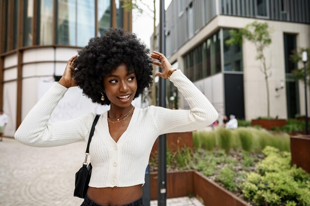 Porträt einer jungen Afrikanerin mit Afrofrisur, die im städtischen Hintergrund lächelt