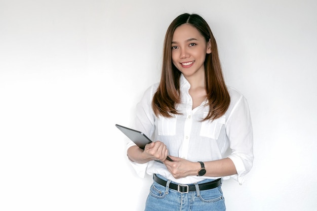 Porträt einer jungen asiatischen Arbeitnehmerin in Freizeitkleidung, die lächelt und ein digitales Tablet hält, das über weißem Hintergrund steht