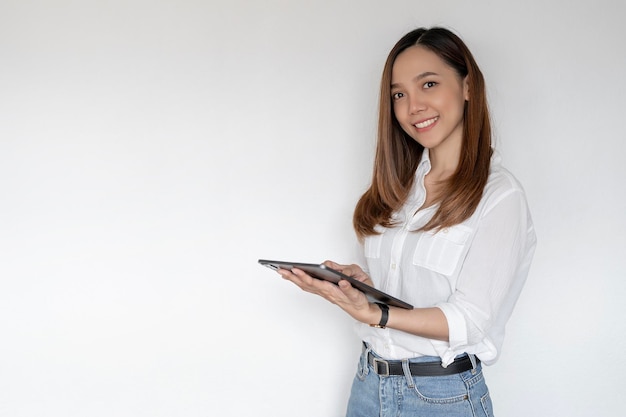 Porträt einer jungen asiatischen Arbeitnehmerin in Freizeitkleidung, die lächelt und ein digitales Tablet hält, das über weißem Hintergrund steht