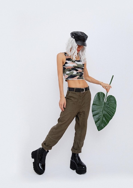 Porträt einer jungen Blondine, die militärische modische Streetstyle-Kleidung und trendige Plateaustiefel trägt. Minimalistische Mode