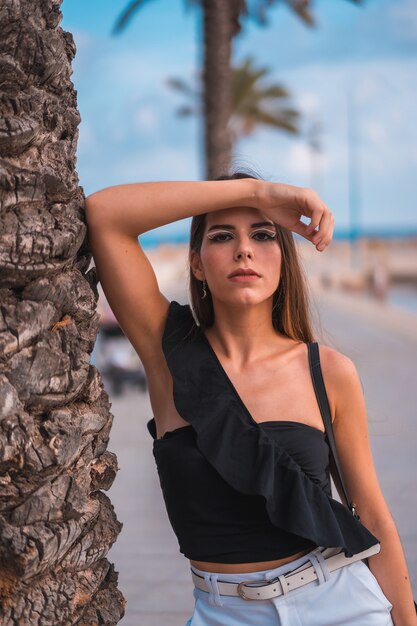 Porträt einer jungen brünetten Frau, die ihren Tag an der Küste am Strand genießt