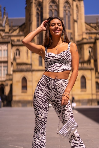 Porträt einer jungen Brünetten in der Stadt im Sommer mit einem Zebra-Print-Jumpsuit-Mode-Lifestyle