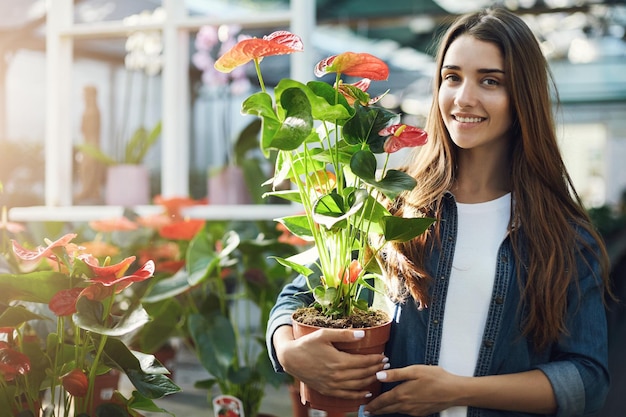 Porträt einer jungen Dame, die eine Blume hält, um sie im Gartenladen zu kaufen