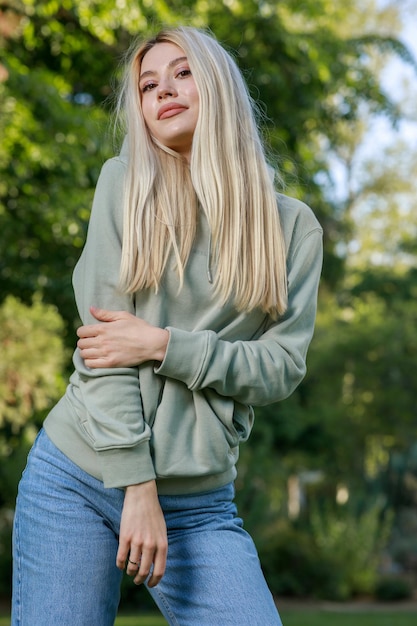 Porträt einer jungen Dame, die im Park steht und in die Kamera lächelt