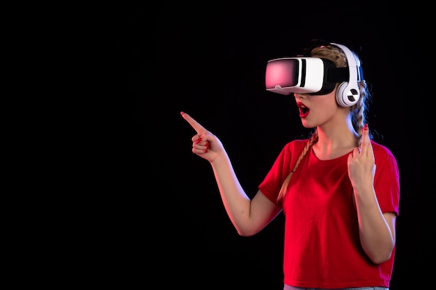 Porträt einer jungen Dame, die vr in Kopfhörern auf dunklem visuellem Ultraschall spielt