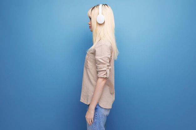 Porträt einer jungen energiegeladenen blonden Frau mit weißen Kopfhörern