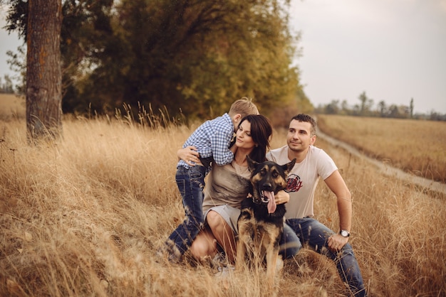 Foto porträt einer jungen familie, die am herbstnachmittag mit einem hund in der natur spielt