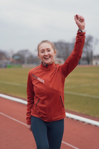 Porträt einer jungen Fitnessfrau, die in einem Leichtathletikstadion läuft