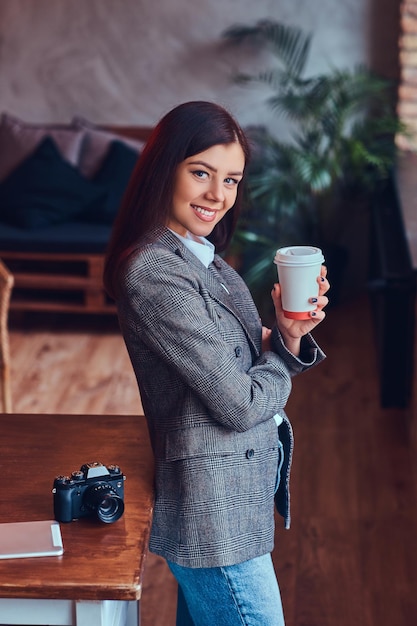 Porträt einer jungen Fotografin hält eine Tasse eines Morgens