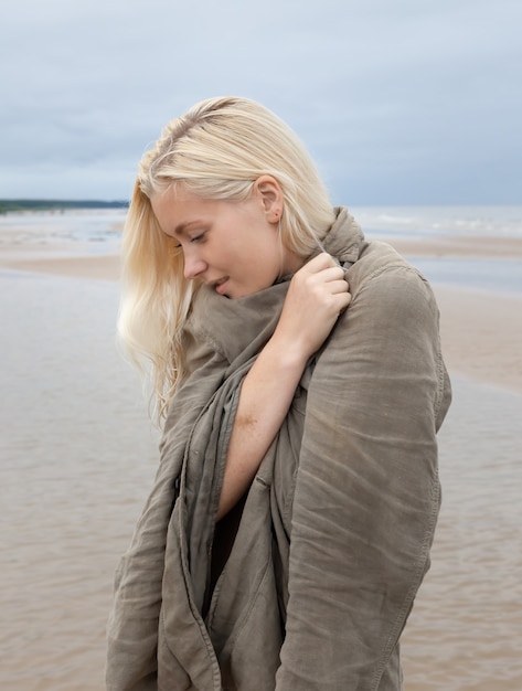 Porträt einer jungen Frau auf Naturhintergrund. Outdoor-Porträt der schönen jungen blonden Frau an der Küste