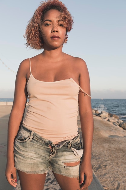 Porträt einer jungen Frau, die am Strand gegen den Himmel steht