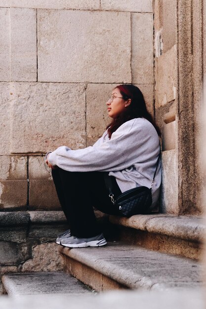 Porträt einer jungen Frau, die an der Wand sitzt