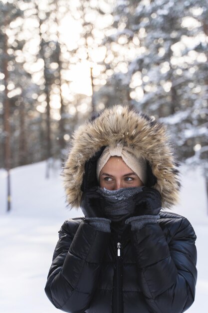 Porträt einer jungen Frau, die an einem kalten Wintertag eine Daunenjacke mit einem Hoodie trägt