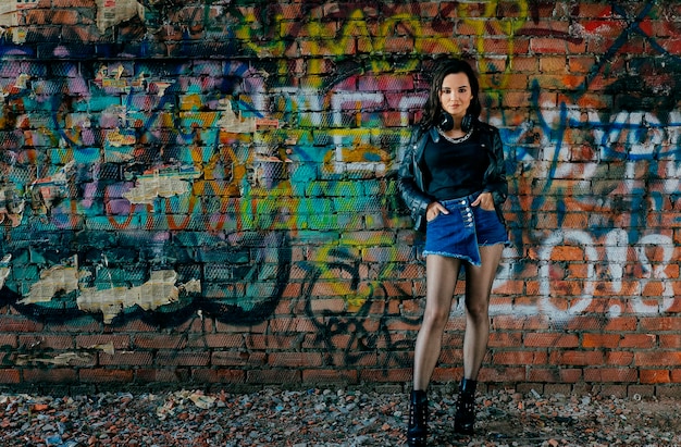 Porträt einer jungen Frau, die an einer Graffiti-Wand steht