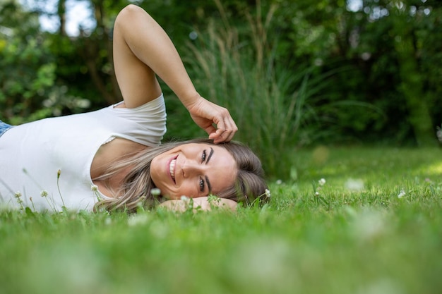 Foto porträt einer jungen frau, die auf dem gras sitzt