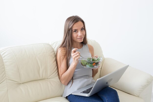 Foto porträt einer jungen frau, die auf dem sofa sitzt und ein telefon benutzt