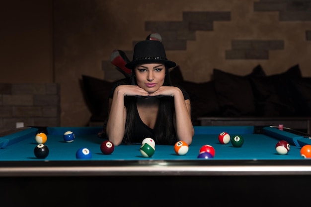 Porträt einer jungen Frau, die auf dem Tisch liegt und Billard spielt