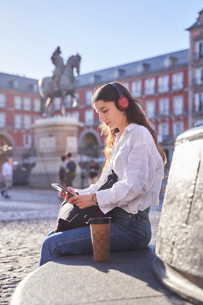 Porträt einer jungen Frau, die auf ein Smartphone schaut, das in Madrid sitzt
