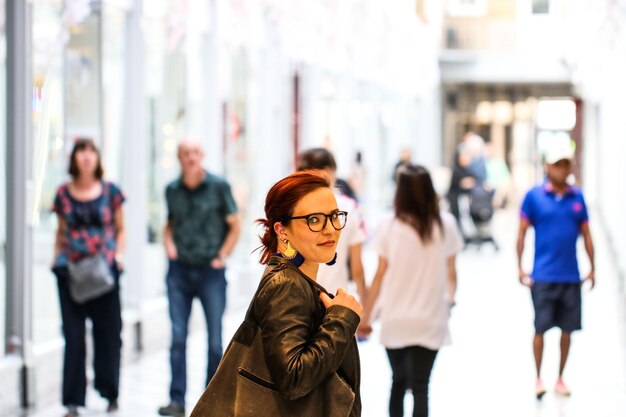 Foto porträt einer jungen frau, die auf einem fußweg in der stadt steht