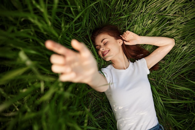 Porträt einer jungen Frau, die auf einem grasbewachsenen Feld liegt