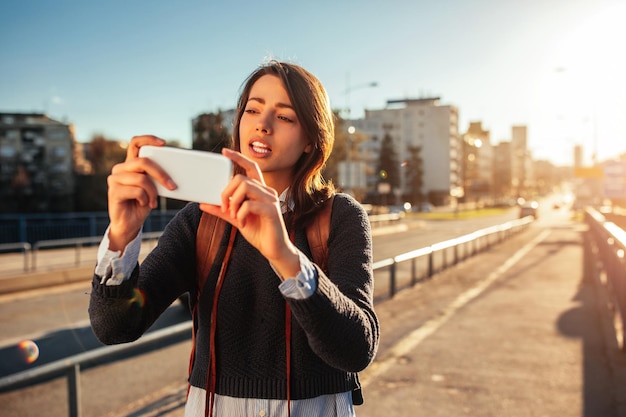 Porträt einer jungen Frau, die beim Sightseeing in einer fremden Stadt ein Mobiltelefon hält