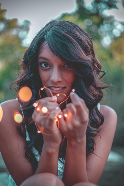 Foto porträt einer jungen frau, die ein beleuchtetes stringlicht hält