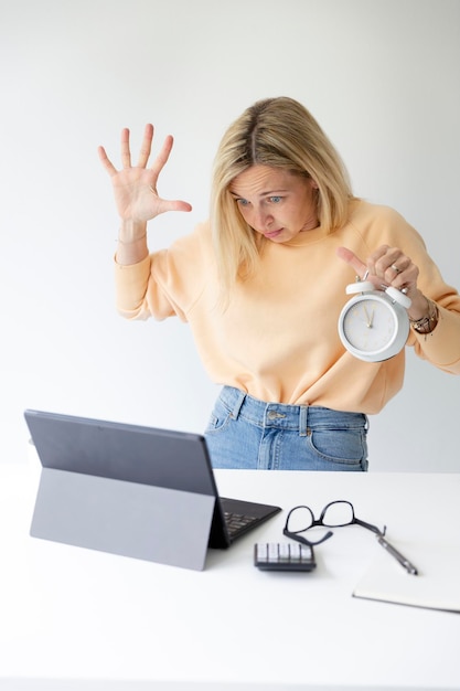 Foto porträt einer jungen frau, die ein digitales tablet benutzt, während sie gegen einen weißen hintergrund steht