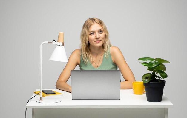 Foto porträt einer jungen frau, die ein digitales tablet benutzt, während sie gegen einen weißen hintergrund steht