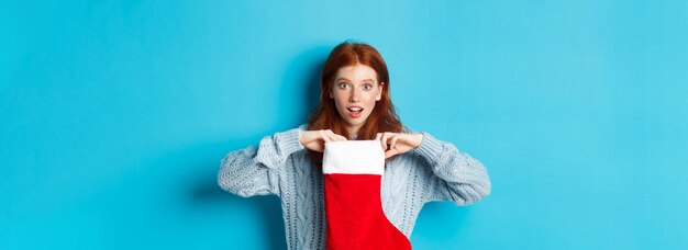 Foto porträt einer jungen frau, die ein geschenk vor blauem hintergrund hält