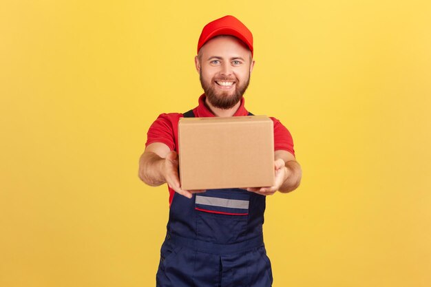 Foto porträt einer jungen frau, die eine kiste vor gelbem hintergrund hält