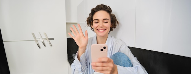 Foto porträt einer jungen frau, die gegen die wand steht und ein handy benutzt