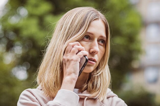 Foto porträt einer jungen frau, die im freien ein mobiltelefon benutzt