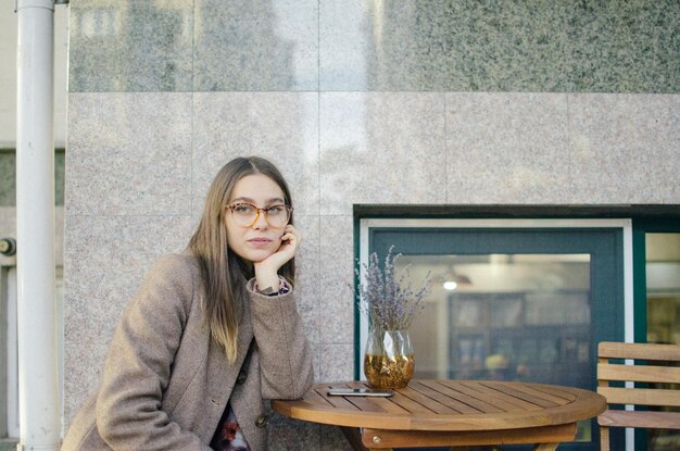 Foto porträt einer jungen frau, die in einem bürgersteigcafé sitzt