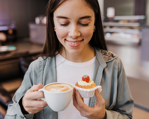 Porträt einer jungen Frau, die Kaffee und Kuchen genießt