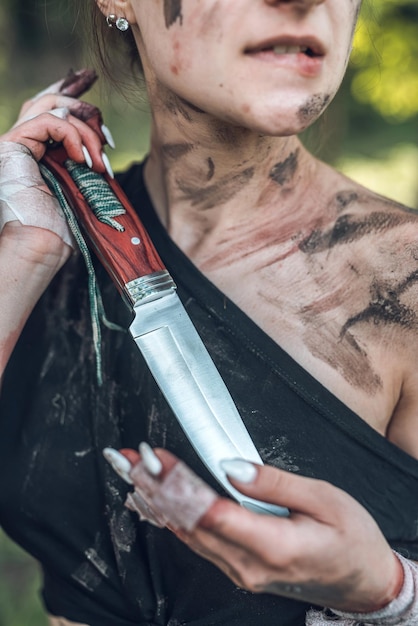 Foto porträt einer jungen frau, die kurze shorts mit messer im wald trägt