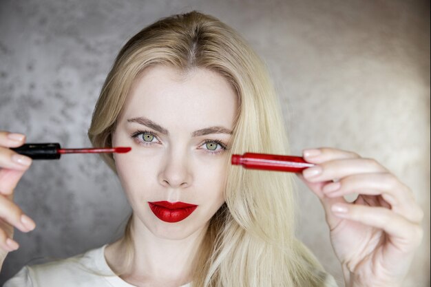 Porträt einer jungen Frau, die Make-up mit leuchtend roten Lippen macht