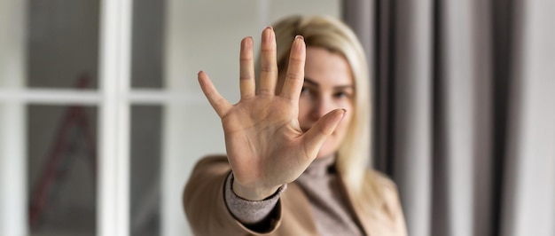 Porträt einer jungen Frau, die mit der Hand ein Stoppschild macht.