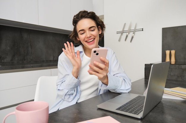 Porträt einer jungen Frau, die mit einem Freund über ein Smartphone Video-Chat führt, die Hand an der Handy-Kamera ruft