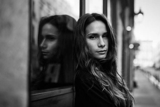 Porträt einer jungen Frau, die sich im Freien am Fenster lehnt