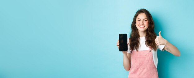 Foto porträt einer jungen frau, die vor blauem hintergrund steht