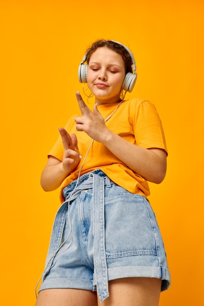Porträt einer jungen Frau, gelbes T-Shirt, Kopfhörer, Unterhaltung, Musik, Spaß, beschnittene Ansicht, unverändert