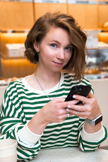 Foto porträt einer jungen frau im café mit handy und blick in die kamera