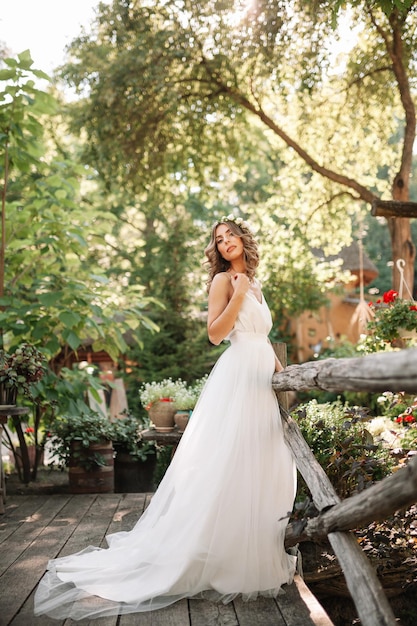 Porträt einer jungen Frau im Hochzeitskleid, die gegen Pflanzen steht