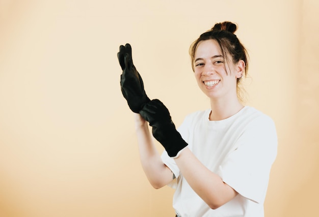 Porträt einer jungen Frau in den 20er Jahren, die Arbeitshandschuhe zum Schutz der Hände während der manuellen Arbeit anzieht, isoliert über gelbem HintergrundMechanikerin in Arbeitskleidung, die starrt Neue Möglichkeiten für Frauen