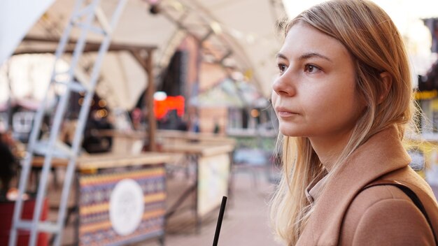 Porträt einer jungen Frau in der Stadt. City Food Court mit Streetfood. Porträt einer Blondine. Lifestyle-Foto