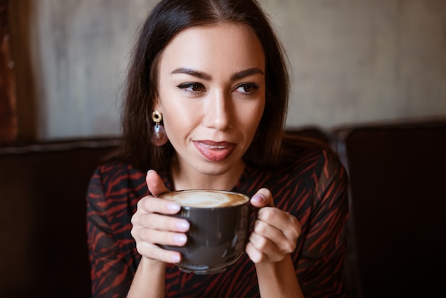 Porträt einer jungen Frau in einem Café mit einer Tasse Kaffee