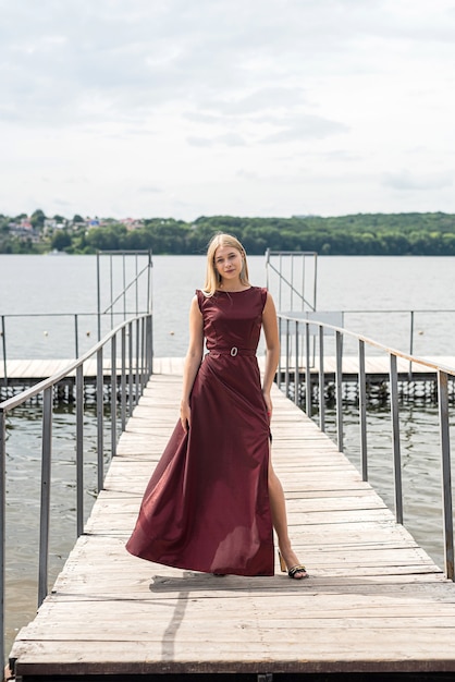 Porträt einer jungen Frau in einem roten Kleid in der Nähe von Teich, entspannen und genießen Sie den heißen Sommertag, Lifestyle