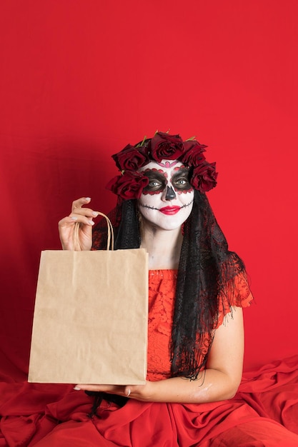Porträt einer jungen Frau in einem roten Kleid und traditionellem Zuckerschädel-Make-up zur Feier des Dia de los Muertos, dem Tag der Toten