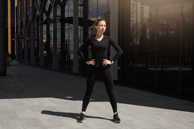 Porträt einer jungen Frau in einem schwarzen Trainingsanzug, die Gymnastik macht