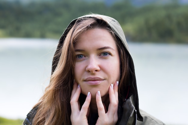 Porträt einer jungen Frau in einer Kapuze bringt ihre Finger ihre Lippen Nahaufnahme